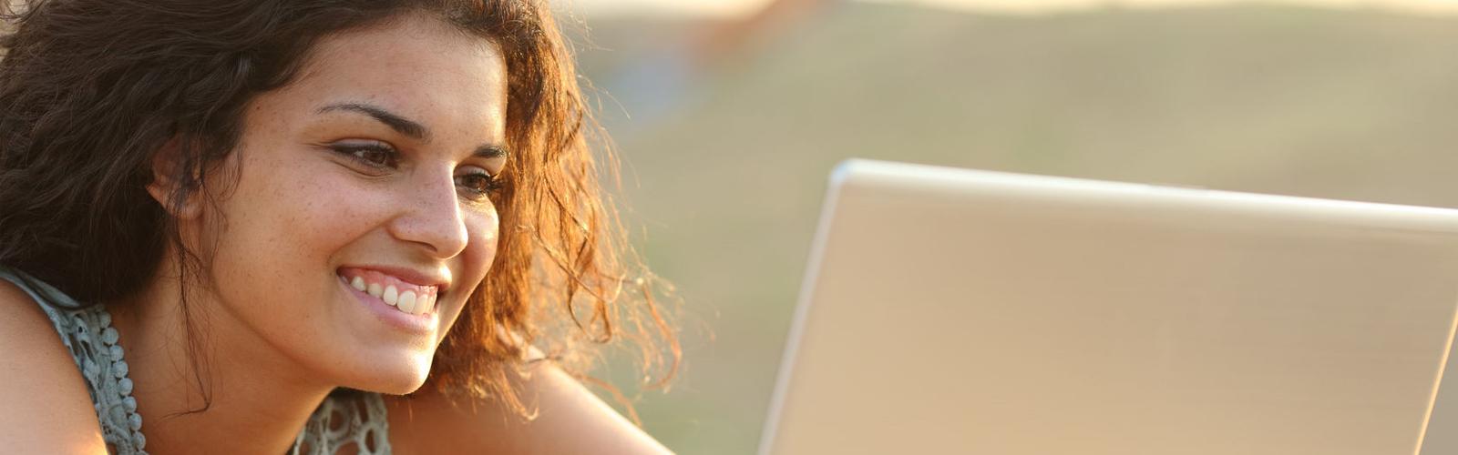 Woman smiling at a computer screen